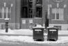 Two dumpsters, with a large '1' and '2' written on them, outside of apartments.